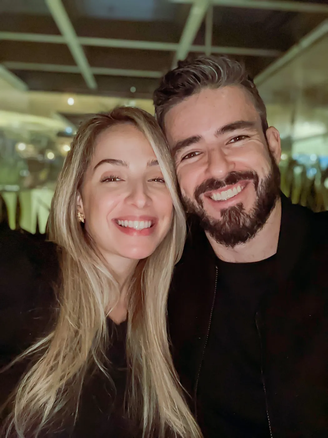 Agnes e Thiago juntinhos, sorrindo, em uma noite