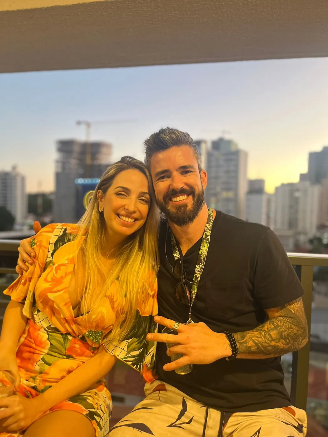 Agnes e Thiago em um rooftop, a cidade ao fundo