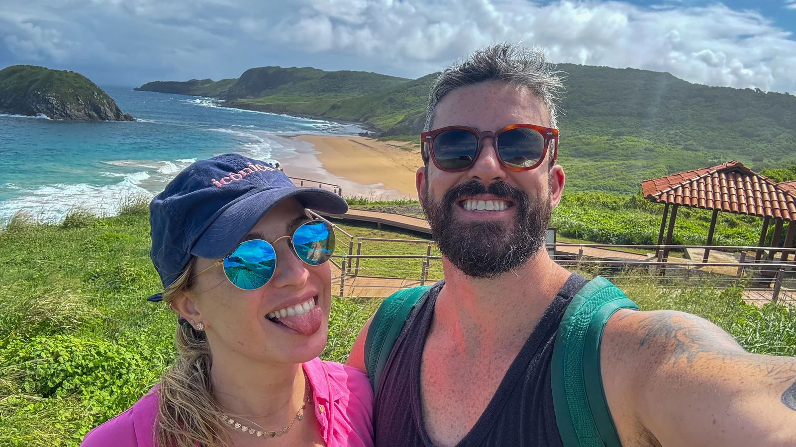 Agnes e Thiago em um mirante verde sobre o mar do litoral