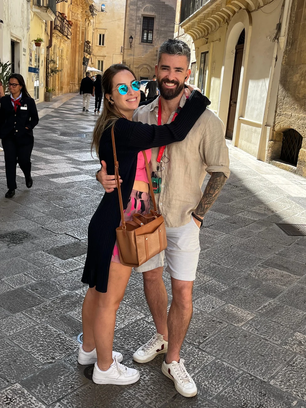 O casal abraçado e rindo em uma rua de pedra de uma cidade antiga